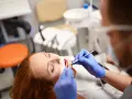 Pacjentka z rudymi włosami u dentysty. Badanie jamy ustnej, które może być związane z diagnostyką twardziny układowej.
