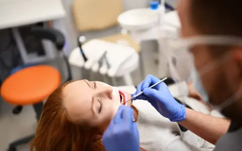 Pacjentka z rudymi włosami u dentysty. Badanie jamy ustnej, które może być związane z diagnostyką twardziny układowej.