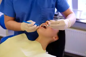 Dentysta wykonuje fluoryzację zębów pacjentki, dbając o ich zdrowie i ochronę przed próchnicą.